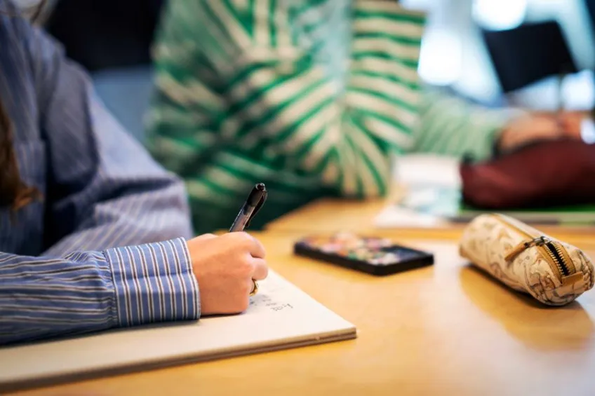 Students at a table taking notes. Photo.